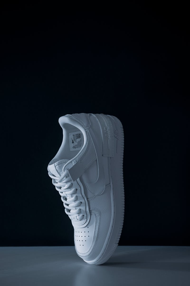 Elevated white sneaker on black background in a studio shoot for fashion and sports.